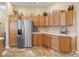 Well-lit kitchen features stainless steel refrigerator, ample wooden cabinetry, and unique decorative accents at 17635 Se 82Nd Annadale Ter, The Villages, FL 32162