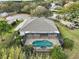 Aerial view of a home showcasing its screened-in pool, lush landscaping, and proximity to a lake at 2031 Capri Ln, Mount Dora, FL 32757