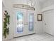 Elegant foyer with decorative glass double doors, white tile flooring, and a stylish light fixture at 2039 Palo Alto Ave, The Villages, FL 32159