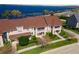 Aerial view of tan townhomes with brown roofs, manicured lawns and a beautiful blue lake in the background at 220 Nautica Mile Dr, Clermont, FL 34711