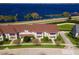 Aerial view of tan townhomes with brown roofs, manicured lawns and a beautiful blue lake in the background at 220 Nautica Mile Dr, Clermont, FL 34711