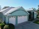 An aerial view of the residence showcasing a two-car garage, turquoise exterior paint scheme and well kept lawn at 25517 Laurel Valley Rd, Leesburg, FL 34748