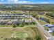 Wide aerial view showcasing neighborhood with a golf course, mature trees, and a lake at 26694 Otter Creek Ln, Leesburg, FL 34748