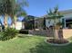 Backyard patio area with brick retaining wall, screened-in lanai, mature palm trees, and landscaping at 26694 Otter Creek Ln, Leesburg, FL 34748