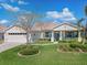 Beautiful home with a two-car garage, white exterior, manicured lawn, and turquoise front door at 26694 Otter Creek Ln, Leesburg, FL 34748