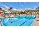 A sparkling pool with lounge chairs, tables and palm trees under a bright blue sky with fluffy white clouds at 26694 Otter Creek Ln, Leesburg, FL 34748