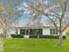 Backyard view of the home with a white exterior and a screened in porch and lush green landscaping at 26821 Augusta Springs Cir, Leesburg, FL 34748