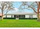 Back exterior of home showing a large green lawn, shrubbery around the building and a tree on the side at 26821 Augusta Springs Cir, Leesburg, FL 34748