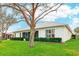 Back exterior of home showing a large green lawn, shrubbery around the building and a tree in the yard at 26821 Augusta Springs Cir, Leesburg, FL 34748