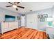 Bedroom featuring hardwood floors, white dresser, mounted TV, and a ceiling fan at 26821 Augusta Springs Cir, Leesburg, FL 34748