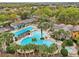 Beautiful aerial view of a community pool with palm trees, seating areas, and clubhouse, ideal for leisure at 26821 Augusta Springs Cir, Leesburg, FL 34748