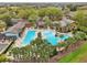 Community pool area with multiple pools, a hot tub, palm trees, seating, and clubhouse, perfect for recreation at 26821 Augusta Springs Cir, Leesburg, FL 34748