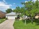 Charming single-story home with a well-manicured lawn, mature tree, and attached two-car garage at 26821 Augusta Springs Cir, Leesburg, FL 34748