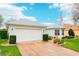 Charming home featuring a pristine two-car garage and meticulously landscaped yard, complete with an American flag at 26821 Augusta Springs Cir, Leesburg, FL 34748