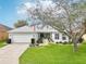 Charming single-story home features a lush lawn, an American flag, mature landscaping, and a two-car garage at 26821 Augusta Springs Cir, Leesburg, FL 34748