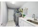 Laundry room equipped with a stainless steel washer and dryer and a white utility sink at 26821 Augusta Springs Cir, Leesburg, FL 34748