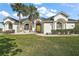 Charming single-story home with lush lawn, palm trees and inviting yellow front door at 288 Bent Oak Ct, Leesburg, FL 34748