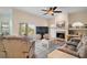Open living room featuring a fireplace, ceiling fan, and sliding glass doors leading to an outdoor pool area at 288 Bent Oak Ct, Leesburg, FL 34748