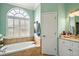 Inviting primary bath with a soaking tub beneath a large window and vanity with marble countertop at 288 Bent Oak Ct, Leesburg, FL 34748