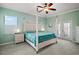 A bright and airy primary bedroom with a four-poster bed, ceiling fan, and access to an outdoor patio at 288 Bent Oak Ct, Leesburg, FL 34748