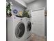 Well-lit laundry room featuring modern washer and dryer, patterned wallpaper, and decorative plants at 3320 Callerton Rd, Clermont, FL 34714