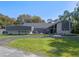 Beautifully designed home with stone accents, gray siding and a well-manicured lawn under a clear blue sky at 36014 Poinsettia Ave, Fruitland Park, FL 34731