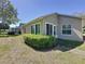 Exterior view of the rear of the house with sliding glass doors and a green, landscaped backyard at 3725 Westerham Dr, Clermont, FL 34711