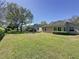 Exterior view of the back of the house with a grassy backyard and some mature shade trees at 3725 Westerham Dr, Clermont, FL 34711