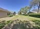 Exterior shot of an expansive backyard featuring a green lawn, shade trees, and house rear views at 3725 Westerham Dr, Clermont, FL 34711