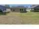 View of the backyard featuring a well-manicured lawn, green shrubbery, and the rear facade of the home at 3725 Westerham Dr, Clermont, FL 34711