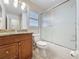 A well-lit bathroom features a wooden vanity, granite countertop, frosted shower doors, and tiled floors at 3725 Westerham Dr, Clermont, FL 34711