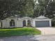 Charming one-story home with a well-manicured lawn, a gray garage door, and lush trees at 3733 Plantation Blvd, Leesburg, FL 34748