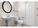 Cozy bathroom featuring a pedestal sink, toilet, and a round wood-trimmed mirror at 37734 N County Road 44A, Eustis, FL 32736