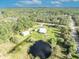 Wide aerial showcasing a home, outbuildings, and pond nestled in lush woods with other waterways nearby at 42141 Chinaberry St, Eustis, FL 32736