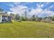 Expansive green backyard with a view of the home, pond, and surrounding trees at 42141 Chinaberry St, Eustis, FL 32736