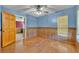 Bedroom with blue walls, wood paneling, ceiling fan with light, and wood floors at 42141 Chinaberry St, Eustis, FL 32736