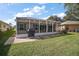 The screened-in patio has outdoor seating and overlooks the lawn with garden space at 509 Grand Vista Trl, Leesburg, FL 34748