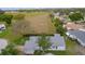 Aerial view of light blue home with a large gray roof, screened-in patio, and grassy fields in the distance at 509 Ventura Ct, The Villages, FL 32159