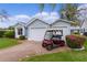 Charming light blue home with a two car garage, a red golf cart, and beautiful landscaping at 509 Ventura Ct, The Villages, FL 32159