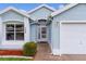 Inviting entrance with decorative glass front door and manicured landscaping leading to the attached garage at 509 Ventura Ct, The Villages, FL 32159