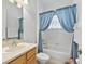 Bathroom featuring wood cabinets, a toilet, a tub and blue curtains for privacy and decor at 5144 Grove Mnr, Lady Lake, FL 32159