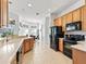 Well-lit kitchen featuring wooden cabinetry, black appliances, and view into the dining area at 5144 Grove Mnr, Lady Lake, FL 32159