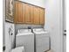 Bright laundry room featuring a stacked washer and dryer, complemented by ample overhead cabinet storage at 5144 Grove Mnr, Lady Lake, FL 32159