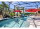 Enclosed pool with hot tub, patio, red umbrellas, and tropical landscaping at 5262 Royce Dr, Mount Dora, FL 32757