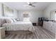 Bedroom with neutral walls, wood-look floors, ceiling fan, and a painting of palm trees above the headboard at 527 Richburg St, The Villages, FL 32162