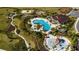 Aerial view of community pool, splashpad, and playground amidst manicured landscaping at 569 Bellflower Way, Clermont, FL 34715