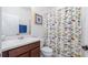 Neutral bathroom with a brown vanity, white toilet and colorful patterned shower curtain at 569 Bellflower Way, Clermont, FL 34715