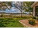 Serene backyard view of lake with mature trees, lush lawn, and mulch flowerbed at 5824 Blue Savannah Dr, Leesburg, FL 34748