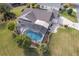 Aerial view of a home featuring a screened-in pool, lush landscaping, and a well-maintained yard at 592 Netherwood Pl, The Villages, FL 32163