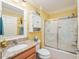 Bathroom with a vanity, toilet, shower with patterned glass doors, and yellow walls at 592 Netherwood Pl, The Villages, FL 32163